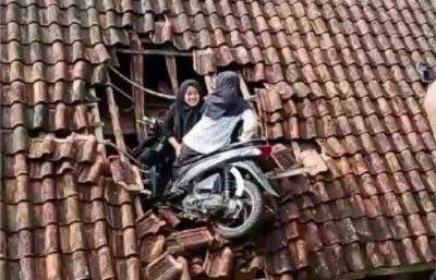 两名女孩和她的摩托车被困在居民家的屋顶上